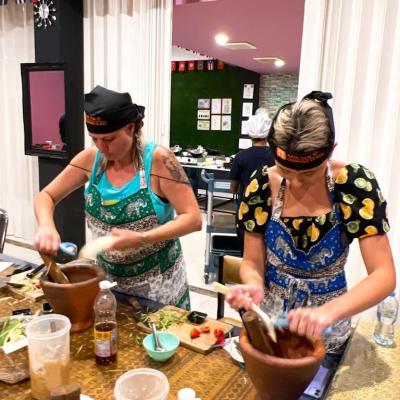 Two people preparing food in a kitchen with flags overhead.