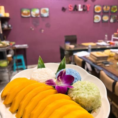 Plate of sliced mango, sticky rice, and orchid garnish on a table.