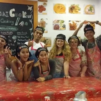 Group of people in aprons and chef hats posing in a cooking class.
